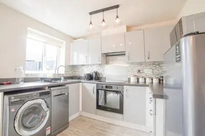 a kitchen with white cabinets and a washer and dryer at Town house Anfield stadium in Liverpool