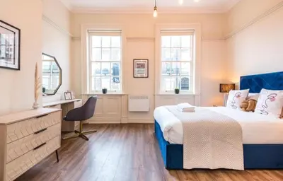 a bedroom with a bed and a desk and windows at 71 Townhouse By Elite in Liverpool