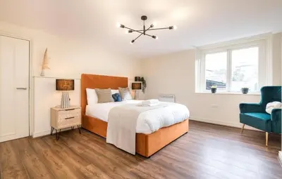 a bedroom with a large bed and a blue chair at 71 Townhouse By Elite in Liverpool