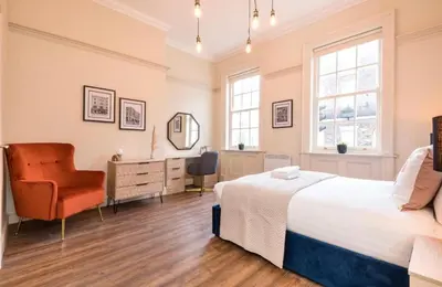 a bedroom with a bed and a chair and a mirror at 71 Townhouse By Elite in Liverpool