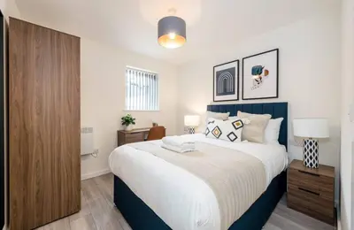 a bedroom with a large bed with a blue headboard at The Coach House by Elite in Liverpool