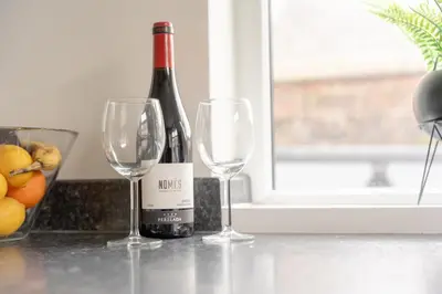 a bottle of wine and two wine glasses on a counter at Clitheroe Wilson Retreat. Central Lancashire in Clitheroe
