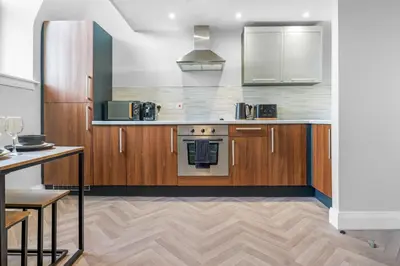 a kitchen with wooden cabinets and a stove at St George's Quarter Stay - Modern City Centre Duplex - Perfect for Business & Leisure - FREE PARKING - WiFi Included - Close to transport links in Liverpool