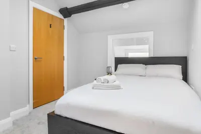 a bedroom with a white bed and a wooden door at St George's Quarter Stay - Modern City Centre Duplex - Perfect for Business & Leisure - FREE PARKING - WiFi Included - Close to transport links in Liverpool