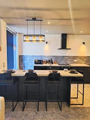 a kitchen with a black island with black chairs at Ocean Breeze in Blackpool