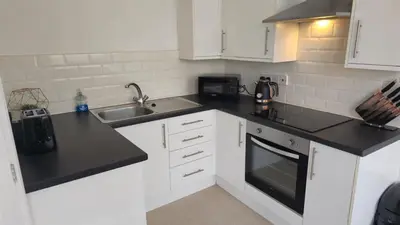 a kitchen with white cabinets and black counter tops at Irwell Chambers by L3 Apartments in Liverpool