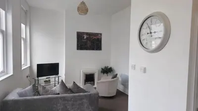 a living room with a couch and a clock on the wall at Irwell Chambers by L3 Apartments in Liverpool