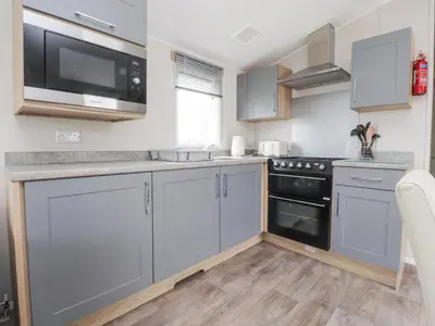 a kitchen with grey cabinets and black appliances at FGH Holidays in Morecambe