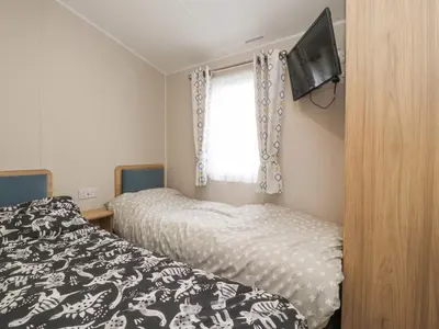 a bedroom with two beds and a tv on the wall at FGH Holidays in Morecambe