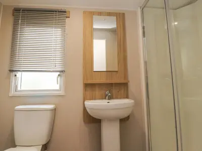 a bathroom with a toilet and a sink and a mirror at FGH Holidays in Morecambe