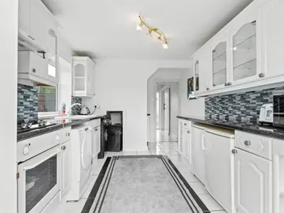 a kitchen with white cabinets and a rug on the floor at Spacious 3 Bedroom Home in Aintree in Liverpool
