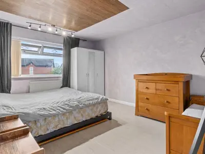 a bedroom with a bed and a dresser and a window at Spacious 3 Bedroom Home in Aintree in Liverpool