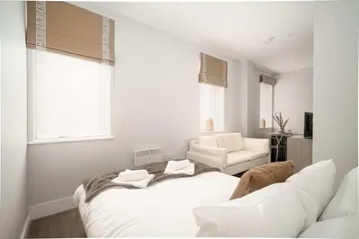 a white bedroom with a bed and a chair at Modern Studio Apartment in Waterloo Liverpool in Liverpool