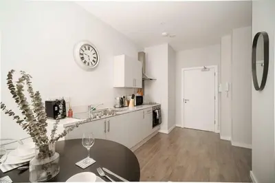 a kitchen with a table and a clock on the wall at Modern Studio Apartment in Waterloo Liverpool in Liverpool
