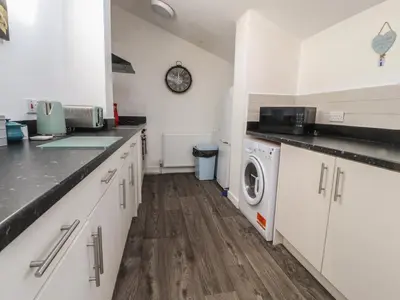 a kitchen with white cabinets and a washer and dryer at Harbour Mews in Lytham St Annes