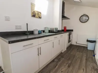 a kitchen with white cabinets and a black counter top at Harbour Mews in Lytham St Annes