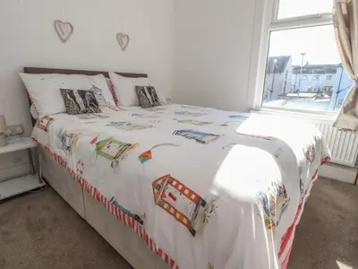 a bedroom with a large white bed with a window at Harbour Mews in Lytham St Annes