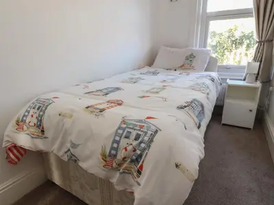 a bedroom with a bed with a white comforter at Harbour Mews in Lytham St Annes