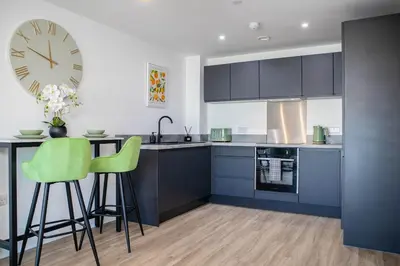 a kitchen with blue cabinets and a clock on the wall at Oriel Suite - Central - Contractors - 6 Beds in Liverpool