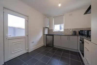 a kitchen with white cabinets and a large door at The place I remember in Liverpool