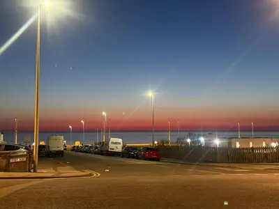 a parking lot with a bunch of trucks parked in front of the ocean at J's Place in Blackpool