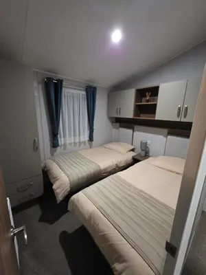 two beds in a small room with blue curtains at Tw Luxury Caravan in Longridge