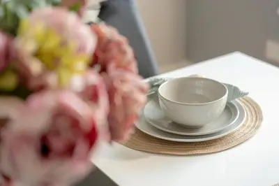 a cup and a plate on a table with flowers at Richmond Terrace - Cosy and Modern Stay in Darwen