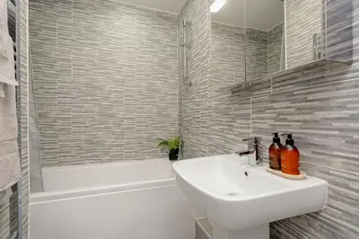 a bathroom with a sink and a toilet and a tub at Richmond Terrace - Cosy and Modern Stay in Darwen