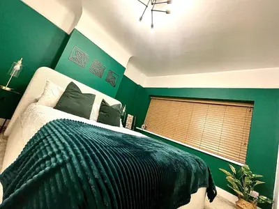 a green bedroom with a bed and a window at Surrey Street Retreat in Wallasey