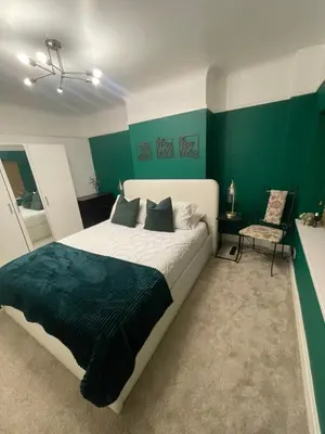 a bedroom with a large bed with green walls at Surrey Street Retreat in Wallasey