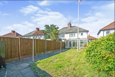 a fence in front of a house with a yard at Surrey Street Retreat in Wallasey