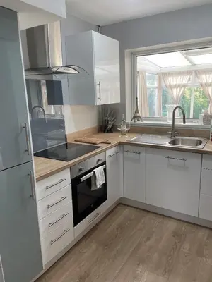 a kitchen with white cabinets and a sink and a window at Surrey Street Retreat in Wallasey