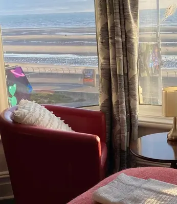 a chair in front of a window with a view of the ocean at The Beachfront Hotel in Blackpool