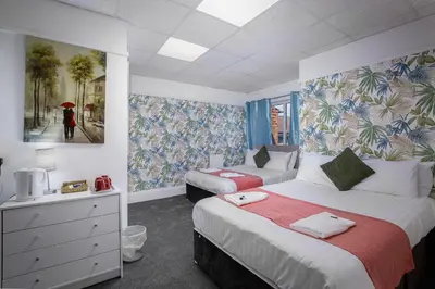 a bedroom with two beds and a woman with an umbrella at The Beachfront Hotel in Blackpool