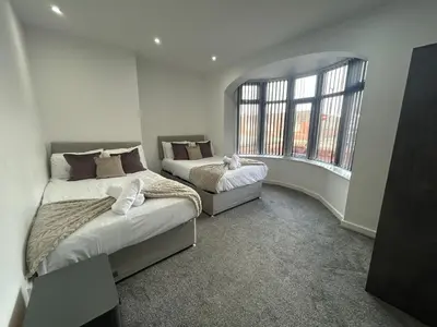 two beds in a room with a window at Luxury Seaside Apartments with Free Parking in Blackpool