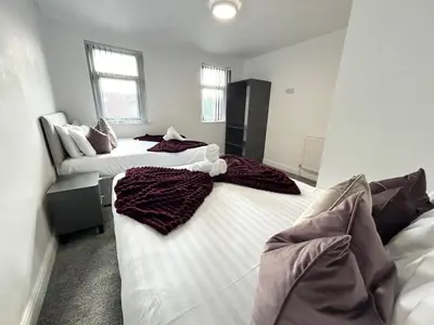 two beds in a room with white walls at Luxury Seaside Apartments with Free Parking in Blackpool