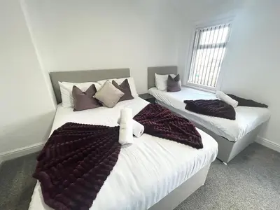 a bedroom with two beds with blankets and pillows at Luxury Seaside Apartments with Free Parking in Blackpool