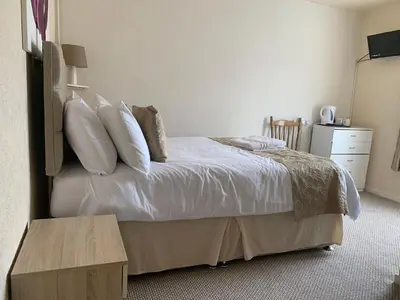 a bedroom with a bed with white sheets and pillows at Sharn Bek Hotel in Blackpool