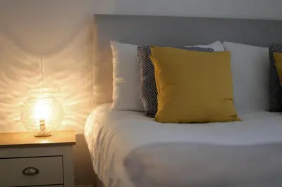 a bed with a yellow pillow and a lamp on a night stand at Avalanche 1 Bed Apartment in Blackpool