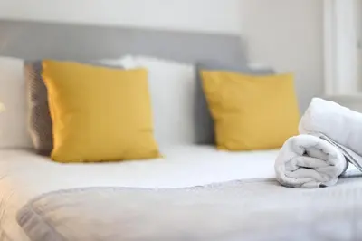 a bed with yellow pillows and a towel at Avalanche 1 Bed Apartment in Blackpool