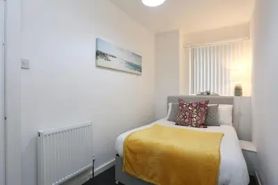 a small bedroom with a bed with a yellow blanket at Big Dipper 2 Bed Pleasure Beach in Blackpool