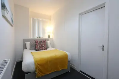 a bedroom with a bed with a yellow blanket on it at Big Dipper 2 Bed Pleasure Beach in Blackpool