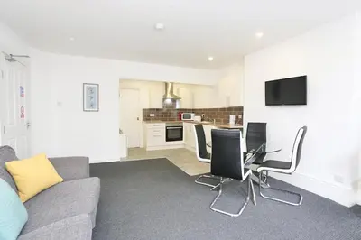 a living room with a couch and chairs and a kitchen at Grand National 1-Bed Very Close to Pleasure Beach in Blackpool