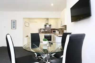 a dining room with a glass table and black chairs at Grand National 1-Bed Very Close to Pleasure Beach in Blackpool