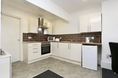 a kitchen with white cabinets and black appliances at Grand National 1-Bed Very Close to Pleasure Beach in Blackpool