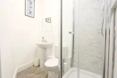 a white bathroom with a toilet and a shower at Ice Blast 1 Bed Pleasure Beach in Blackpool