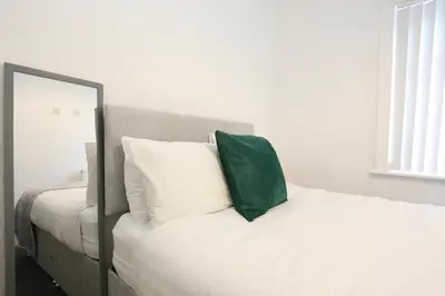 a white bed with a green pillow on top of it at Ice Blast 1 Bed Pleasure Beach in Blackpool