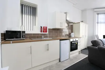 a kitchen with white cabinets and a microwave at Pepsi Max 3 Bed Apartment 2 Bathroom close to Pleasure Beach in Blackpool