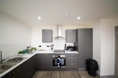 a kitchen with gray cabinets and a stove top oven at Spacious 2 Bedroom Apartment in Central Preston in Preston