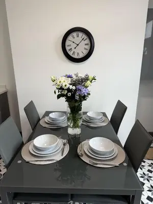 a dining room table with plates and a clock on the wall at 3BR Accommodation in St Helens - Sleeps 6 in Saint Helens